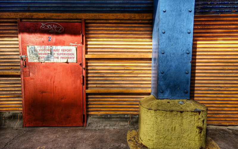 Red door with graffiti and metal shutters