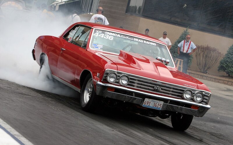 Red drag racing car performing burnout