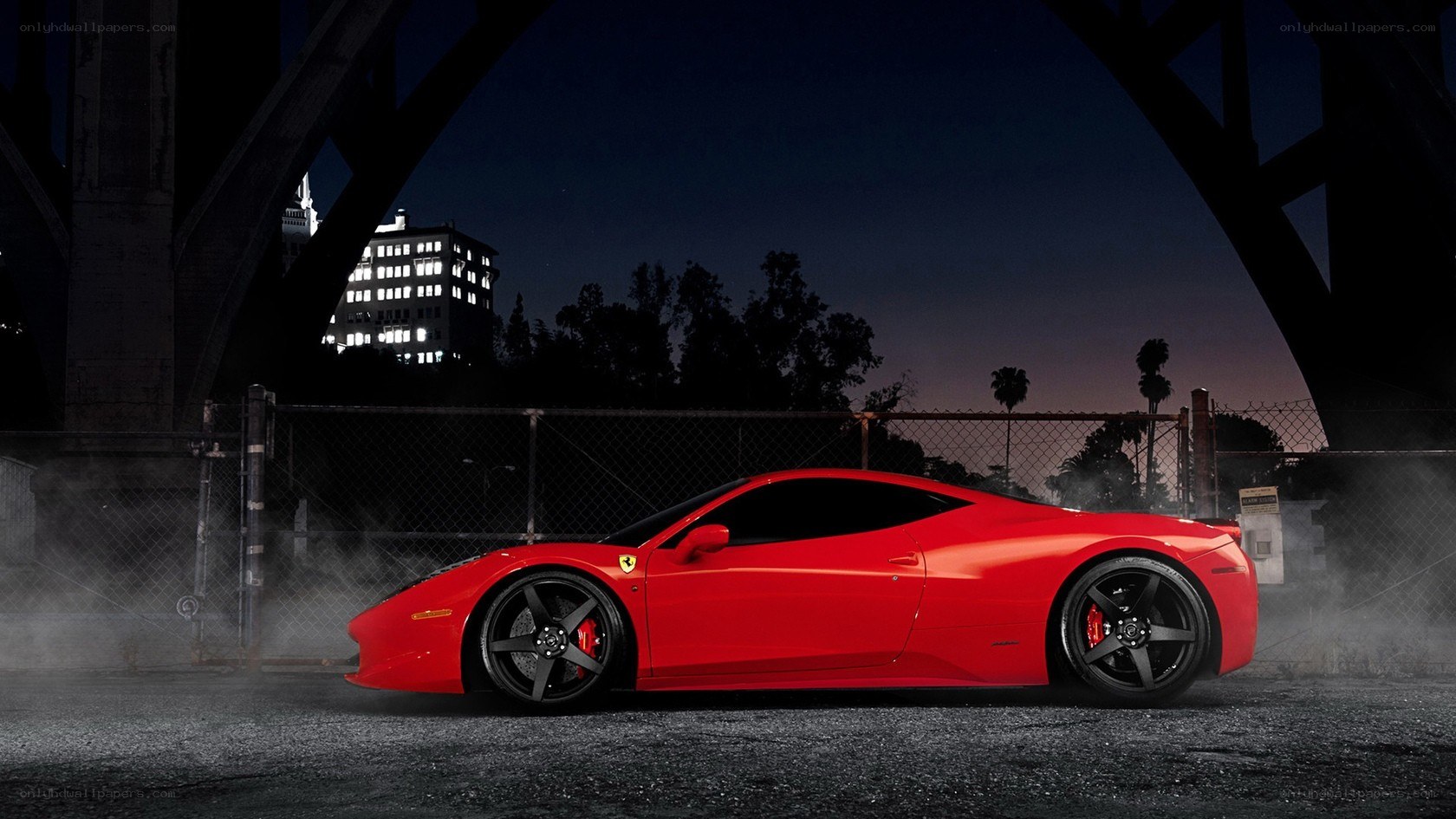 Red Ferrari at night under bridge