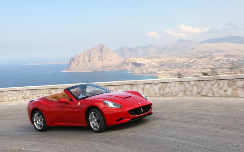Red Ferrari convertible on coastal road