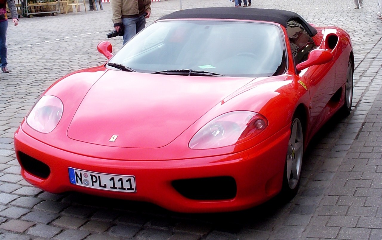 red ferrari convertible on cobblestones