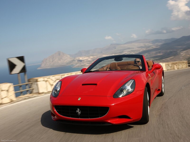 Red Ferrari driving on coastal road