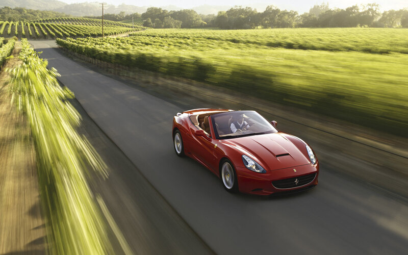 Red Ferrari driving through vineyard