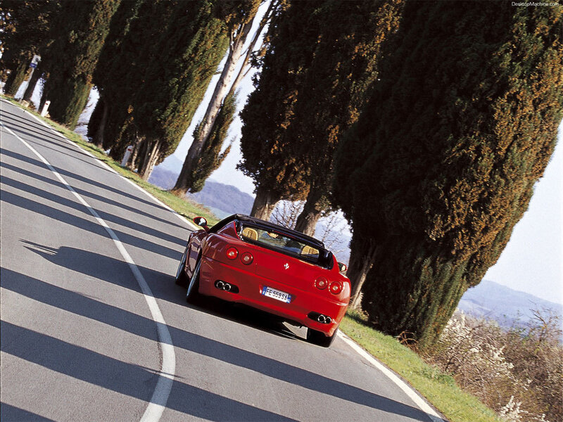 Red Ferrari on a tree-lined road