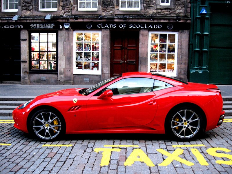 Red Ferrari parked on a cobblestone street