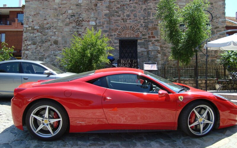 Red Ferrari parked on cobblestone