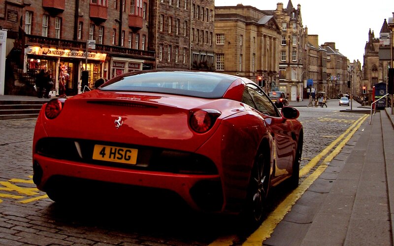 Red Ferrari parked on cobblestone street