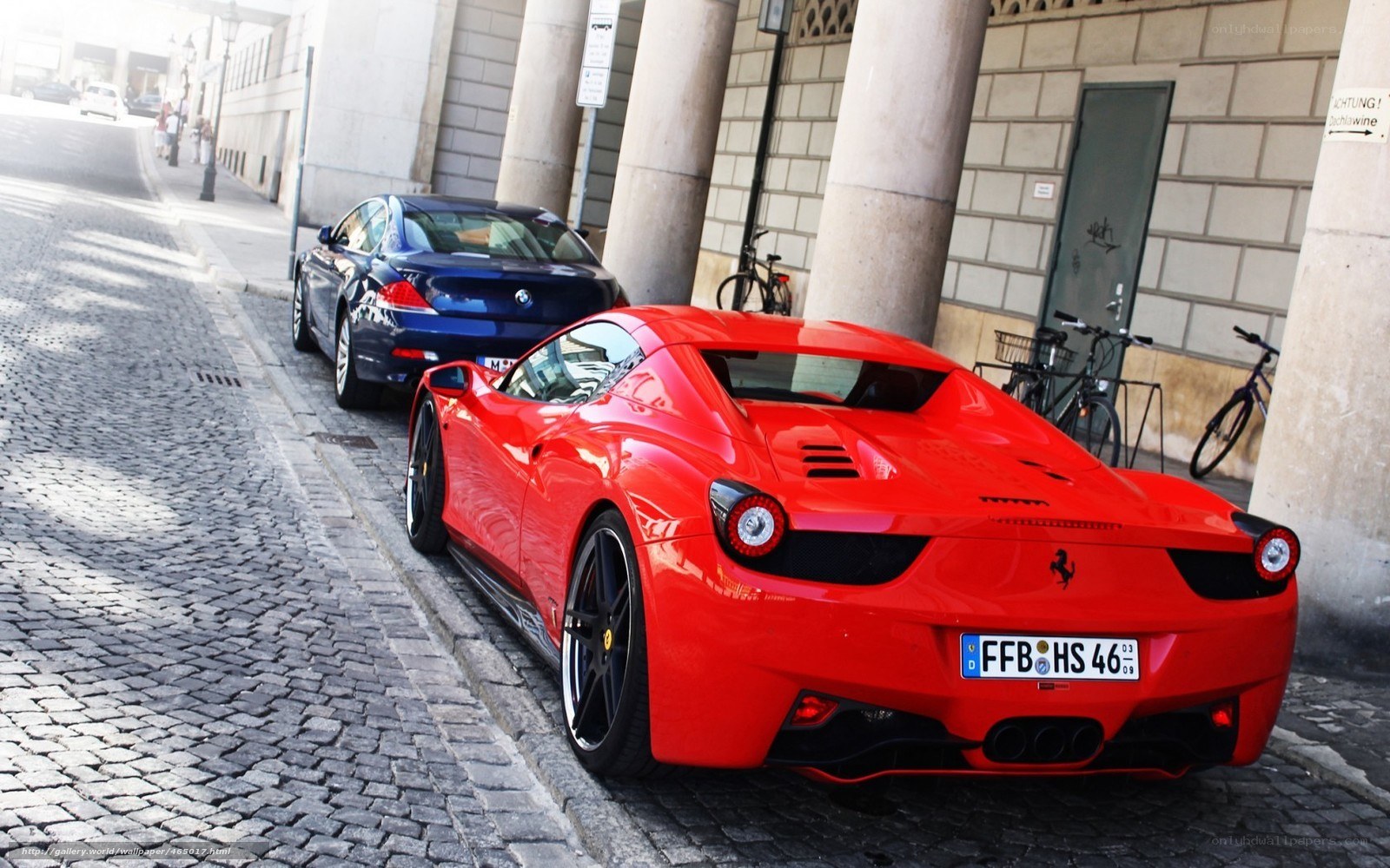 Red Ferrari parked on cobblestone street