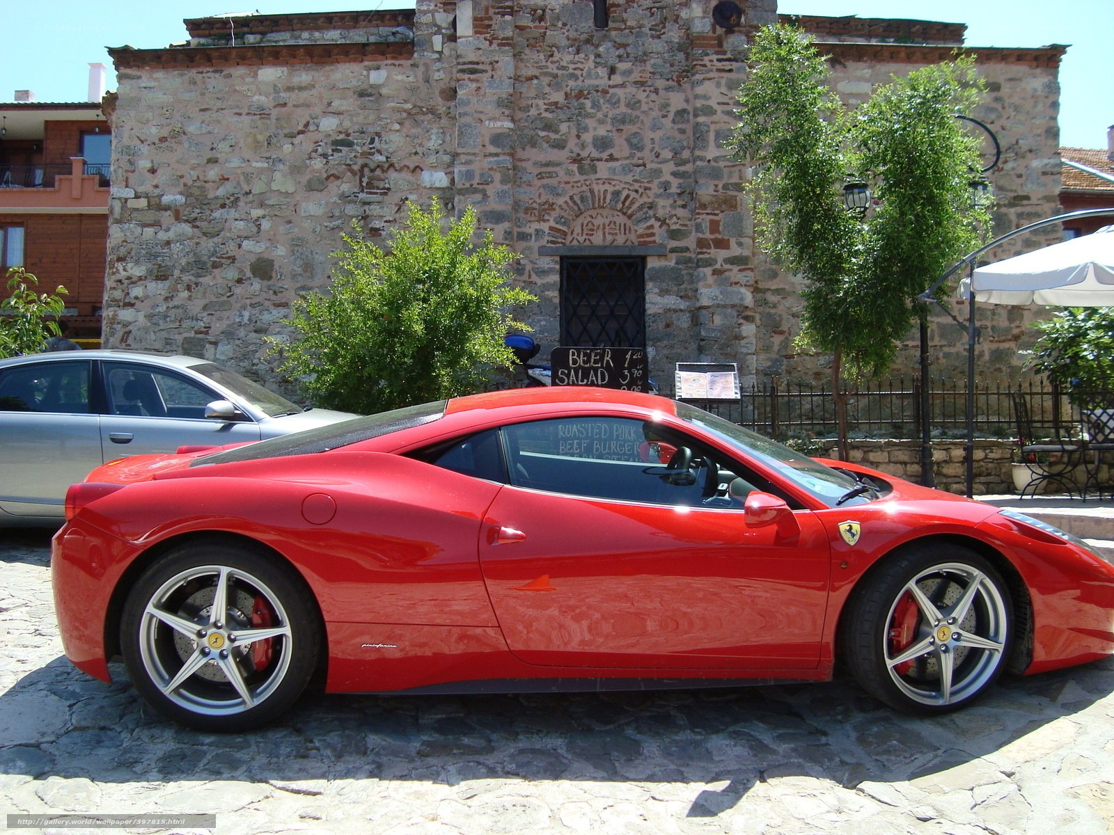 Red Ferrari parked on cobblestones