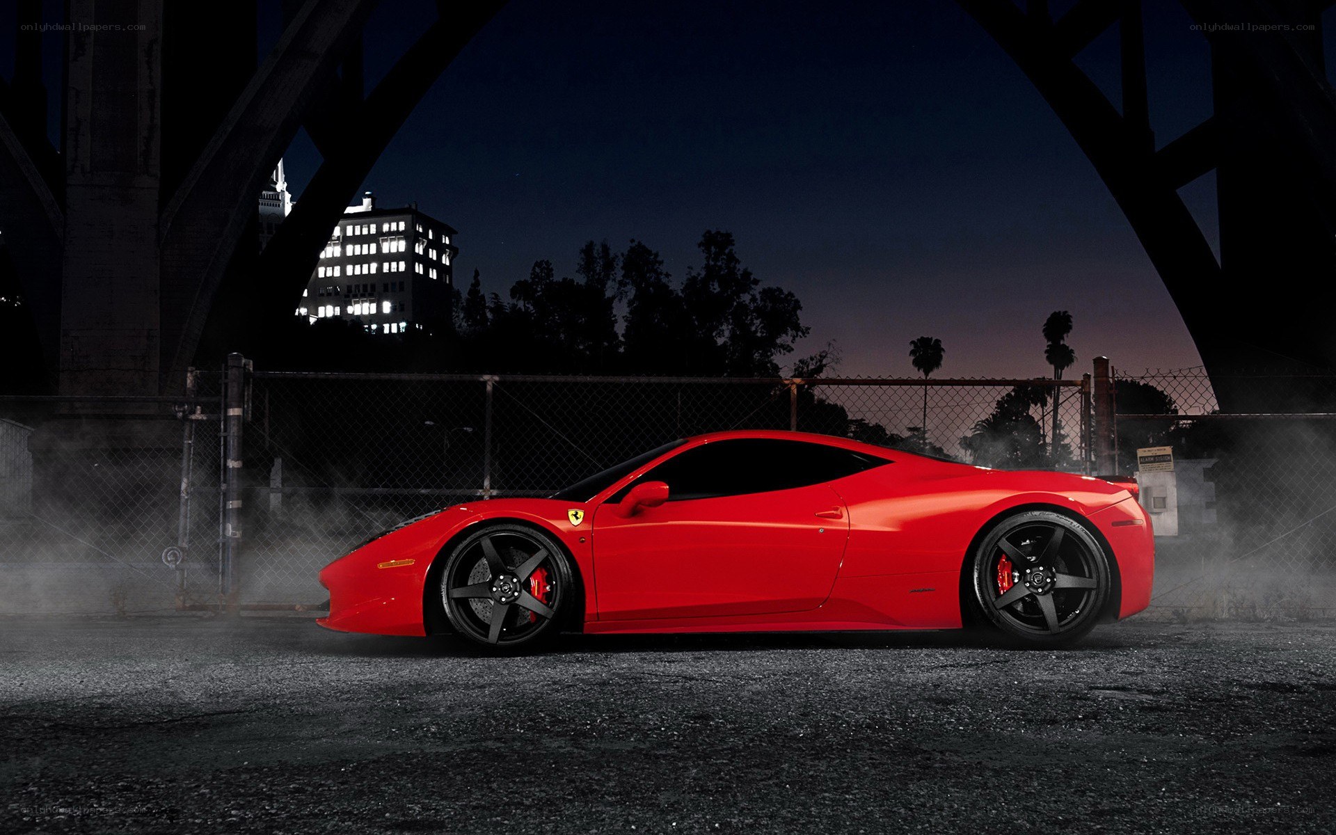 Red Ferrari under a bridge at night