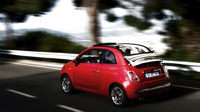 Red Fiat driving on a road