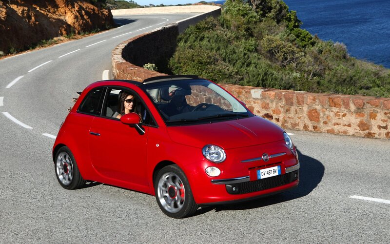 Red Fiat driving on coastal road