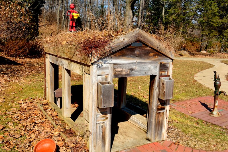 Red Figure on Wooden Shed