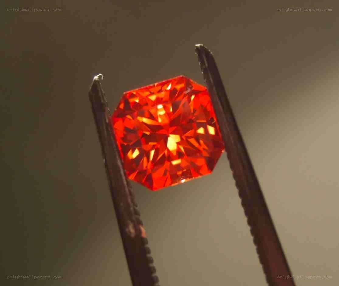 Red gemstone held in tweezers