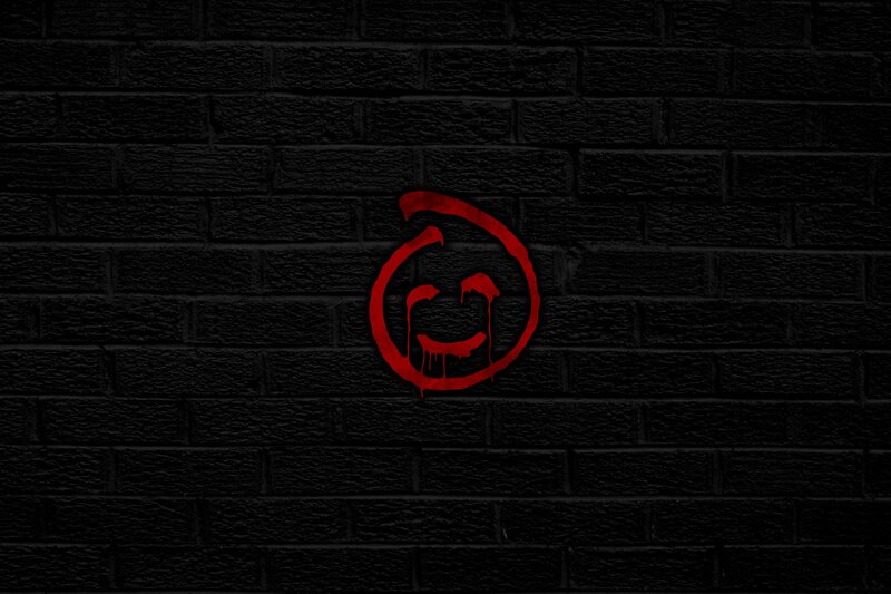 red graffiti smiley on brick wall