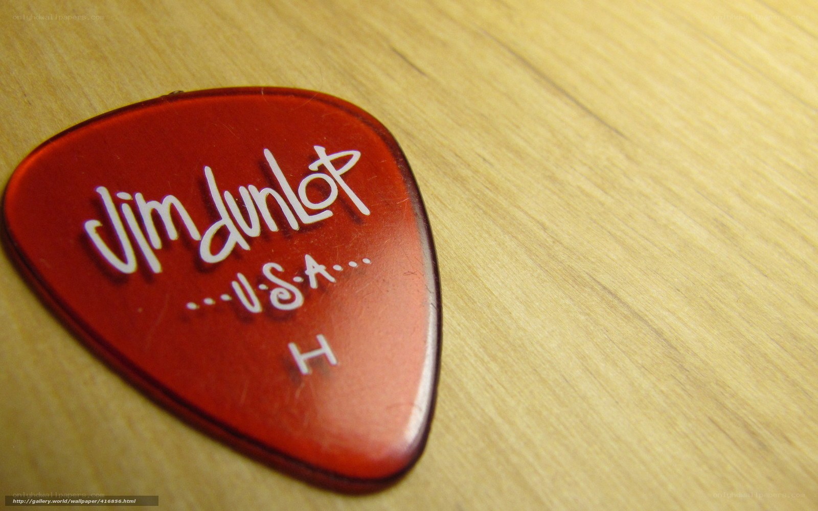 red guitar pick on wood