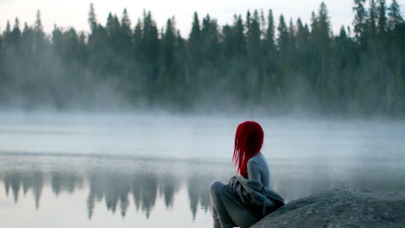 Red-haired person by a misty lake