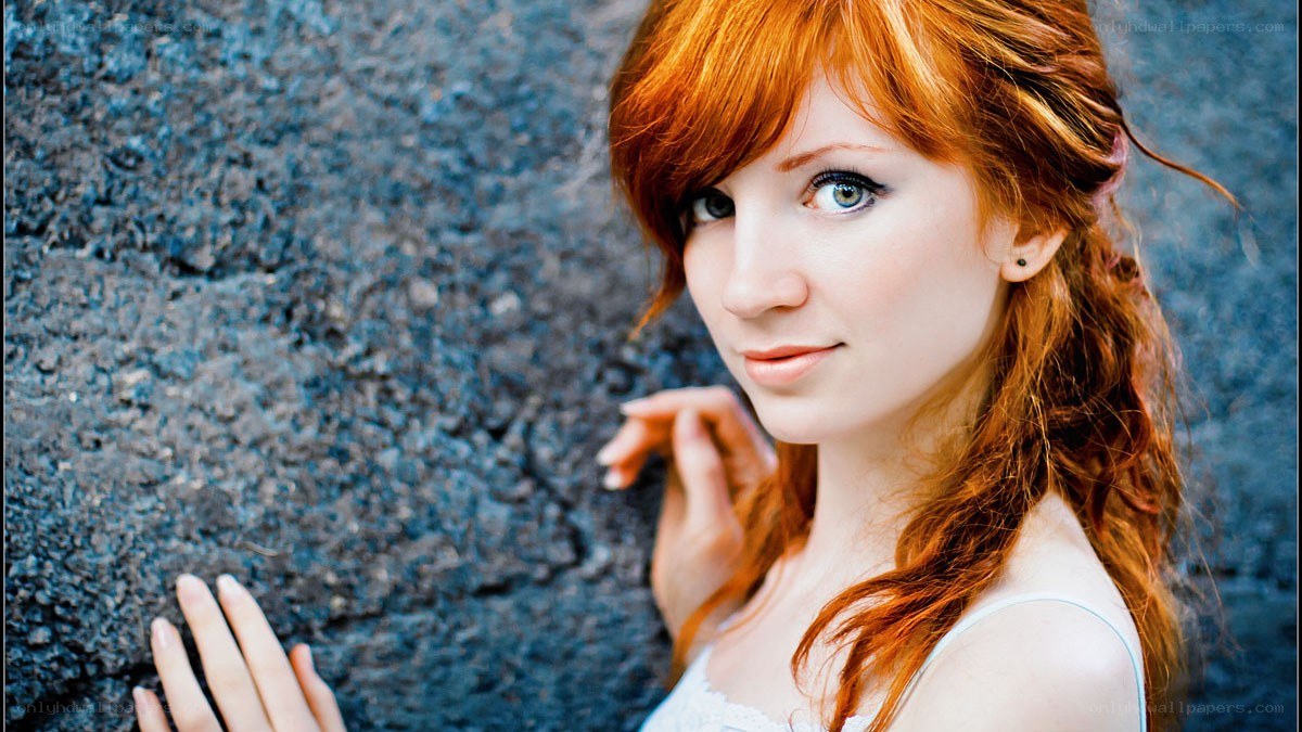 Red-haired woman by a wall
