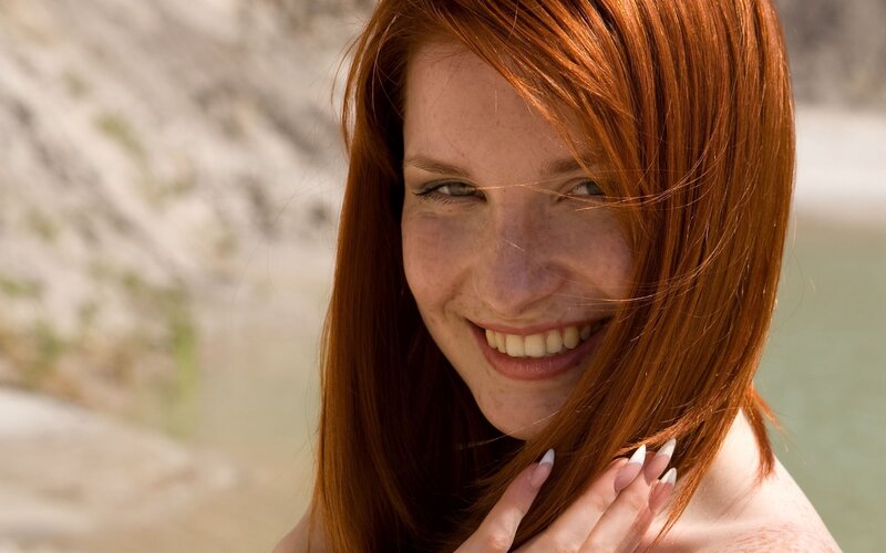 red-haired woman smiling outdoors