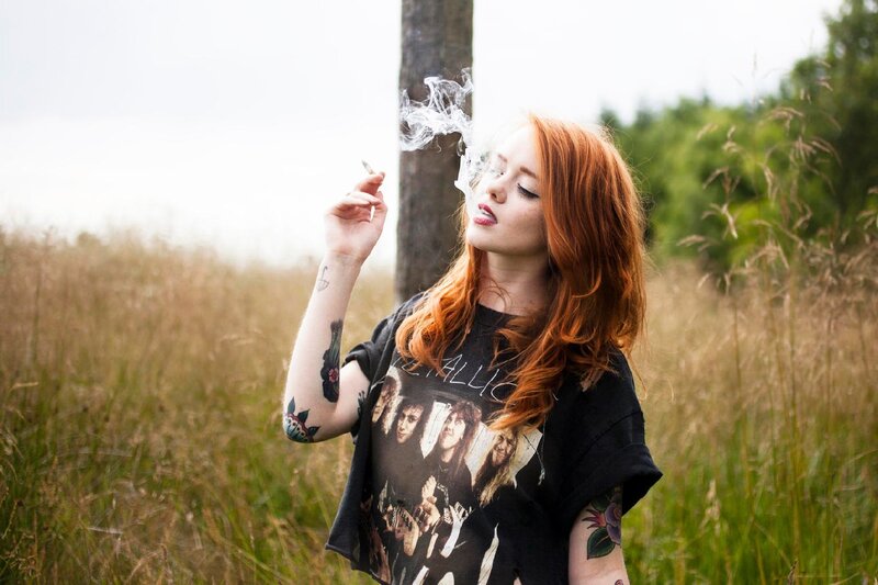 Red-haired woman smoking in field
