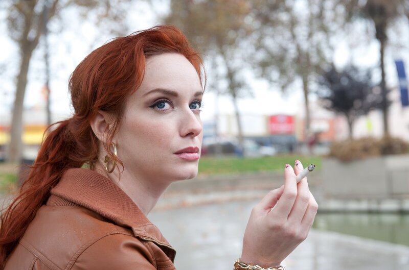 Red-haired woman smoking outdoors