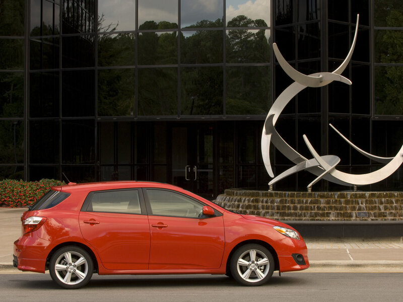 Red hatchback car in front of building