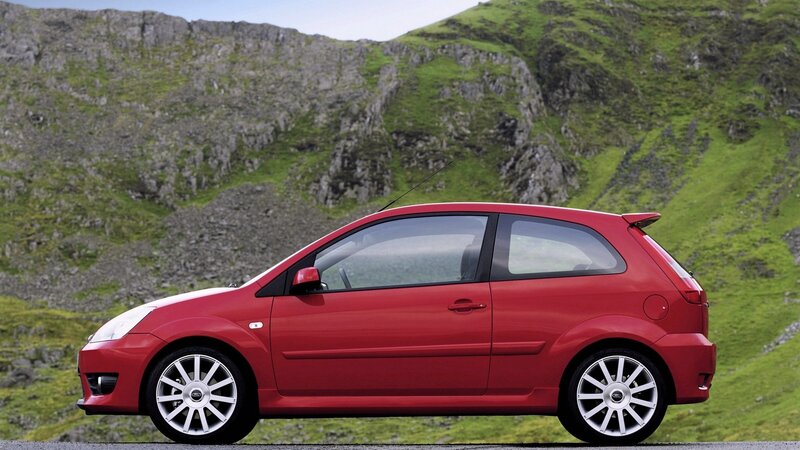 Red hatchback car on mountain road