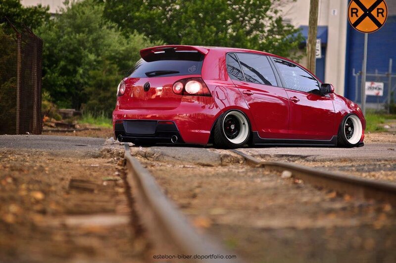 Red hatchback on train tracks