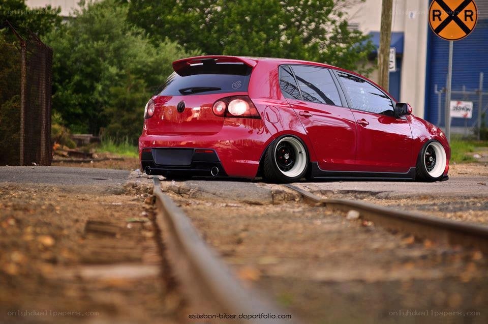 Red hatchback on train tracks
