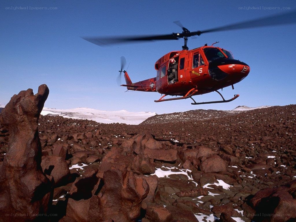 Red helicopter over rocky terrain