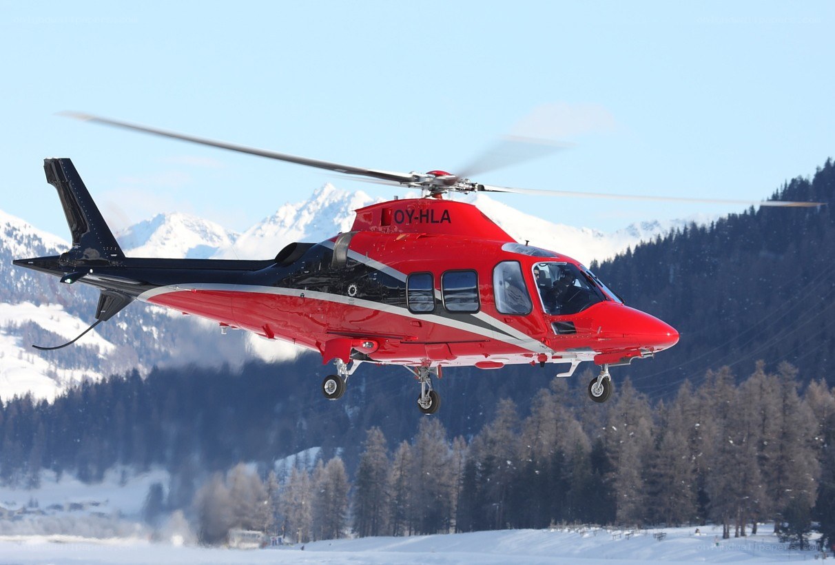 Red helicopter over snowy mountains
