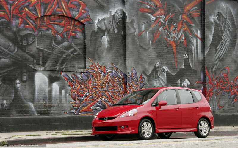 Red Honda Fit in front of graffiti wall