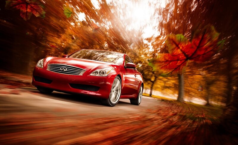 Red Infiniti driving on autumn road