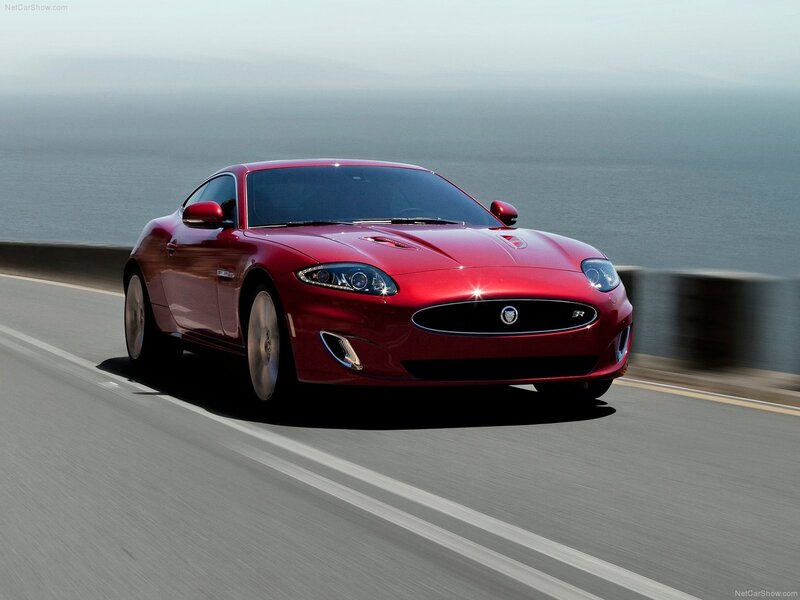 Red Jaguar XK driving on coastal road