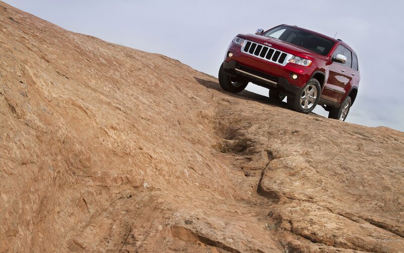 Red Jeep climbing rocky hill