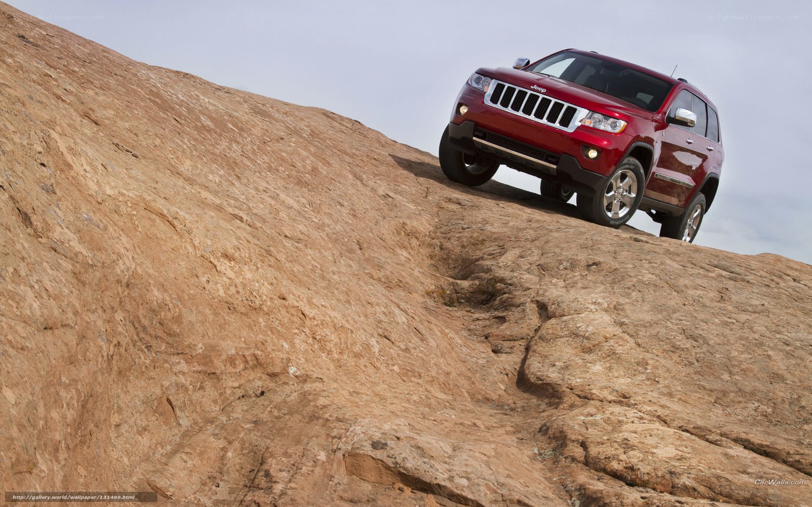 Red Jeep climbing rocky hill