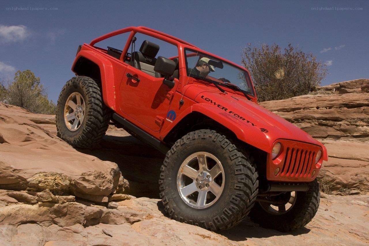Red Jeep climbing rocky terrain