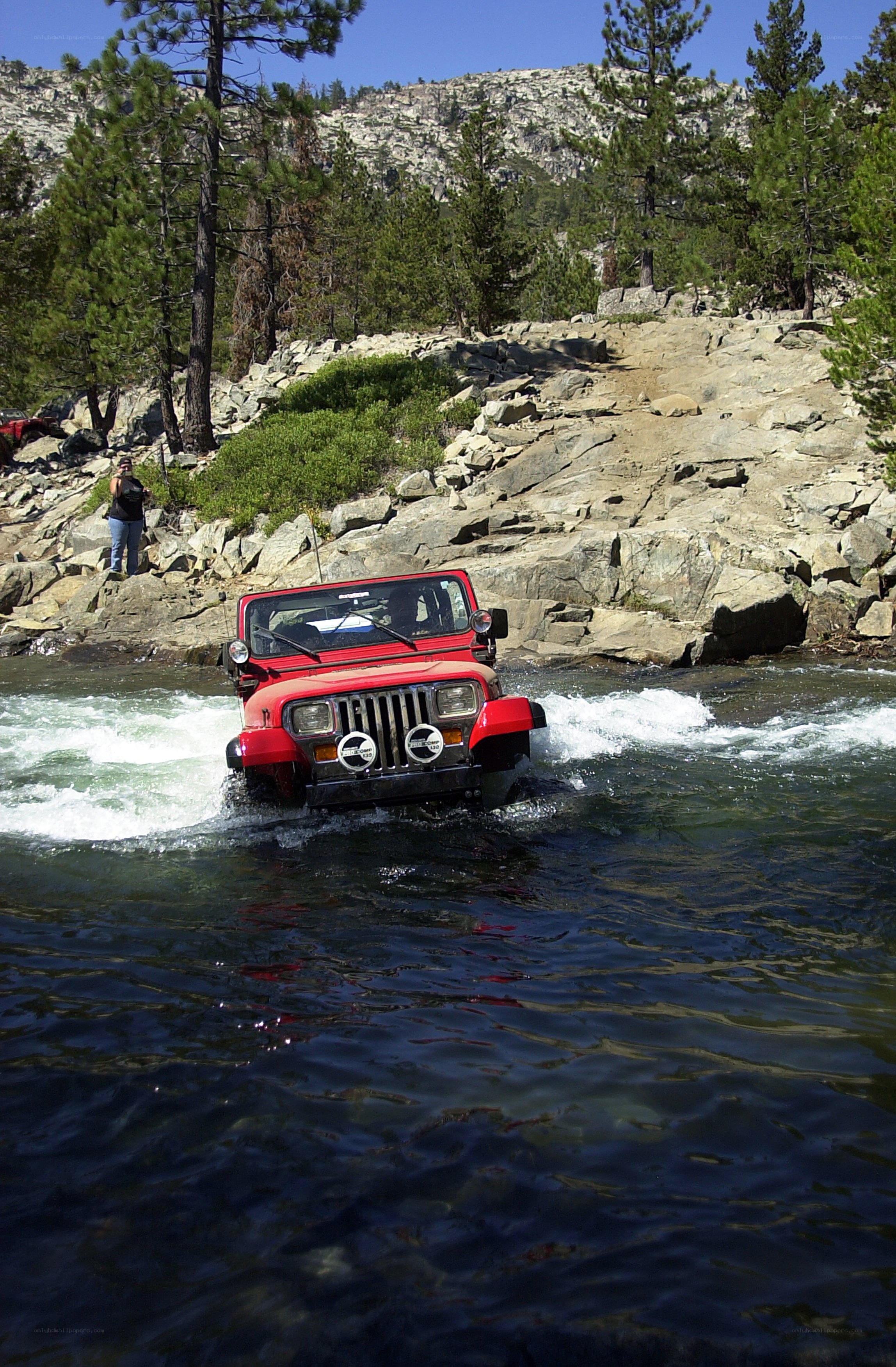 Red jeep crossing a river