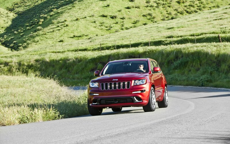 Red Jeep driving on a country road