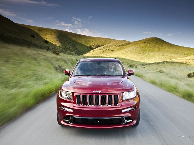 Red Jeep driving on a country road
