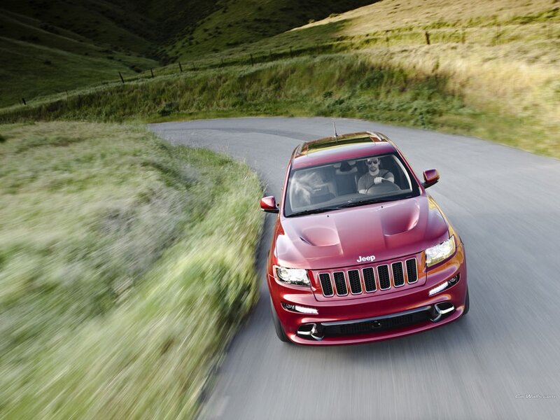 Red Jeep driving on a winding road