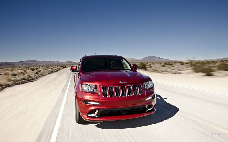 Red Jeep driving on desert road