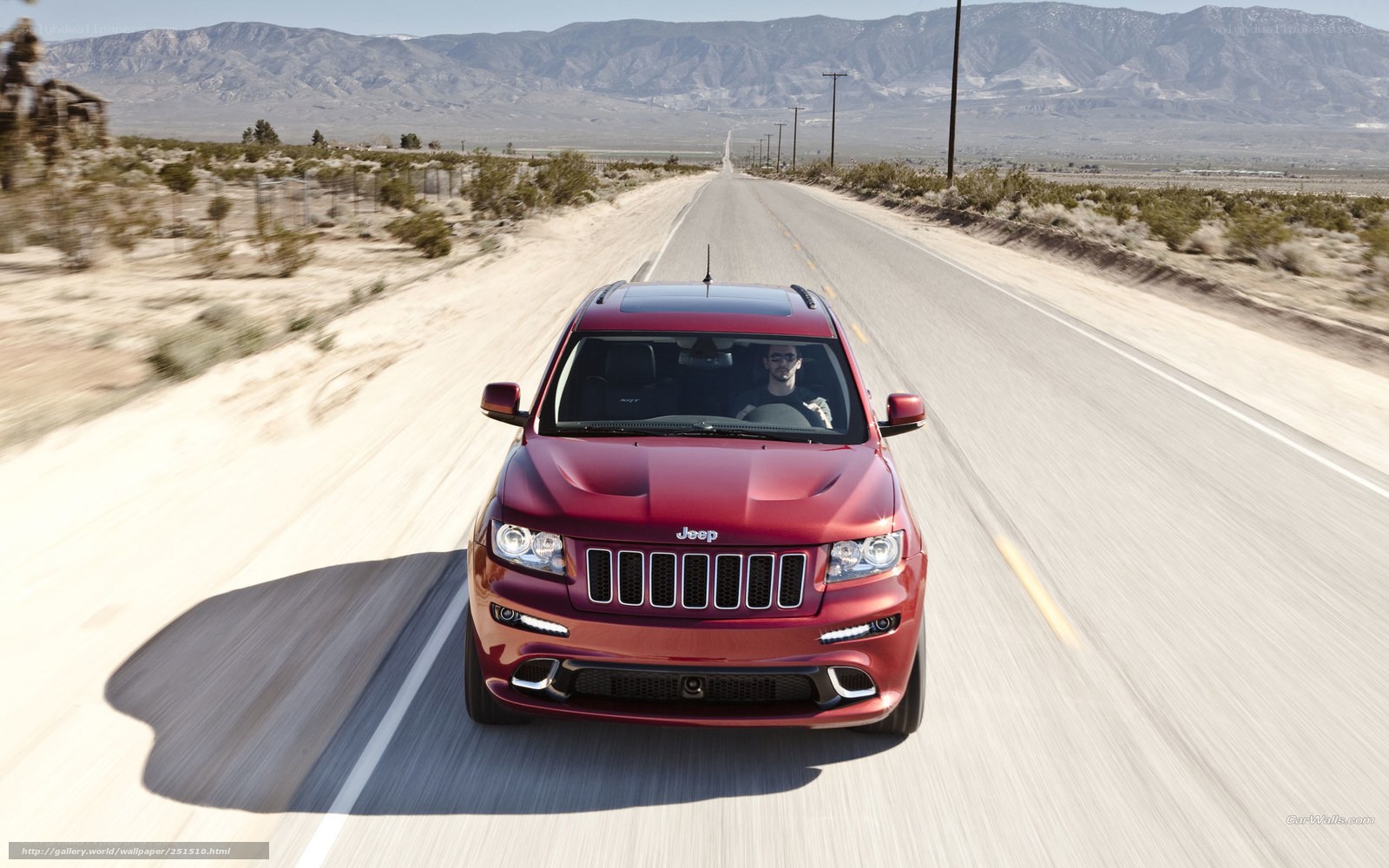 Red Jeep driving on desert road