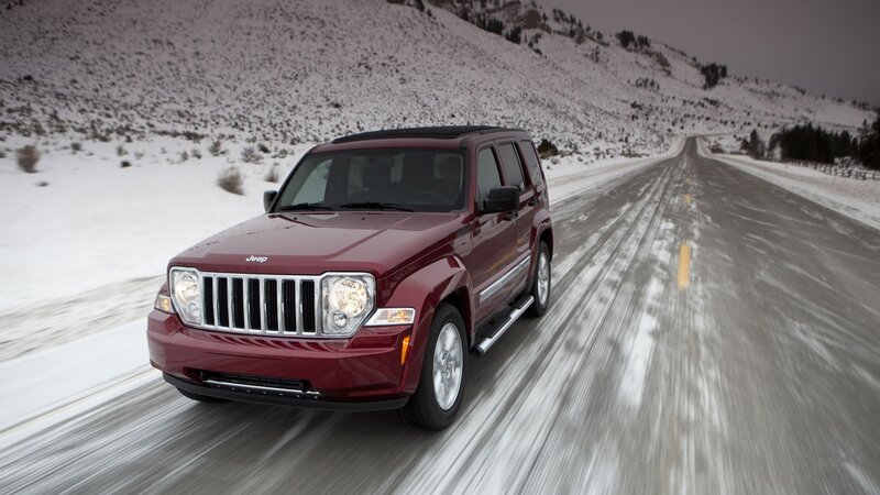 Red Jeep driving on snowy road