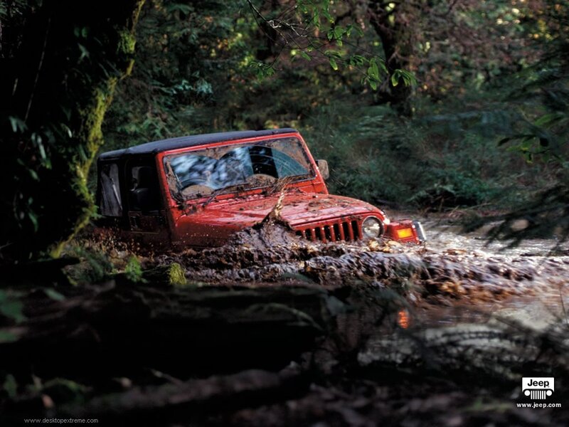 Red jeep driving through mud