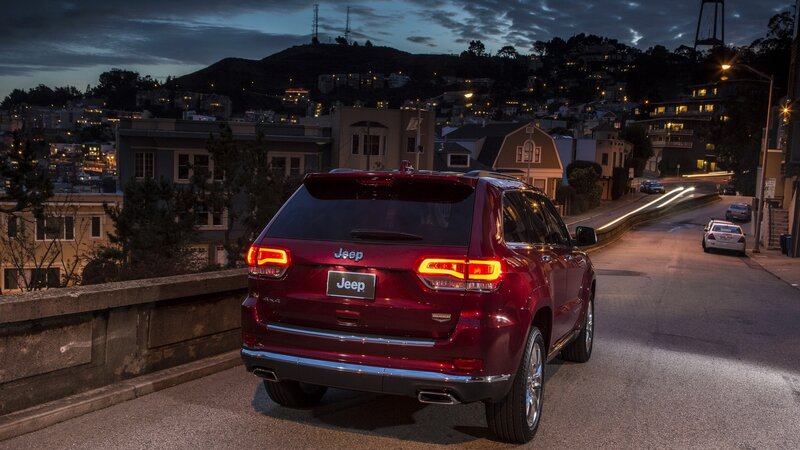 Red Jeep on city street at dusk