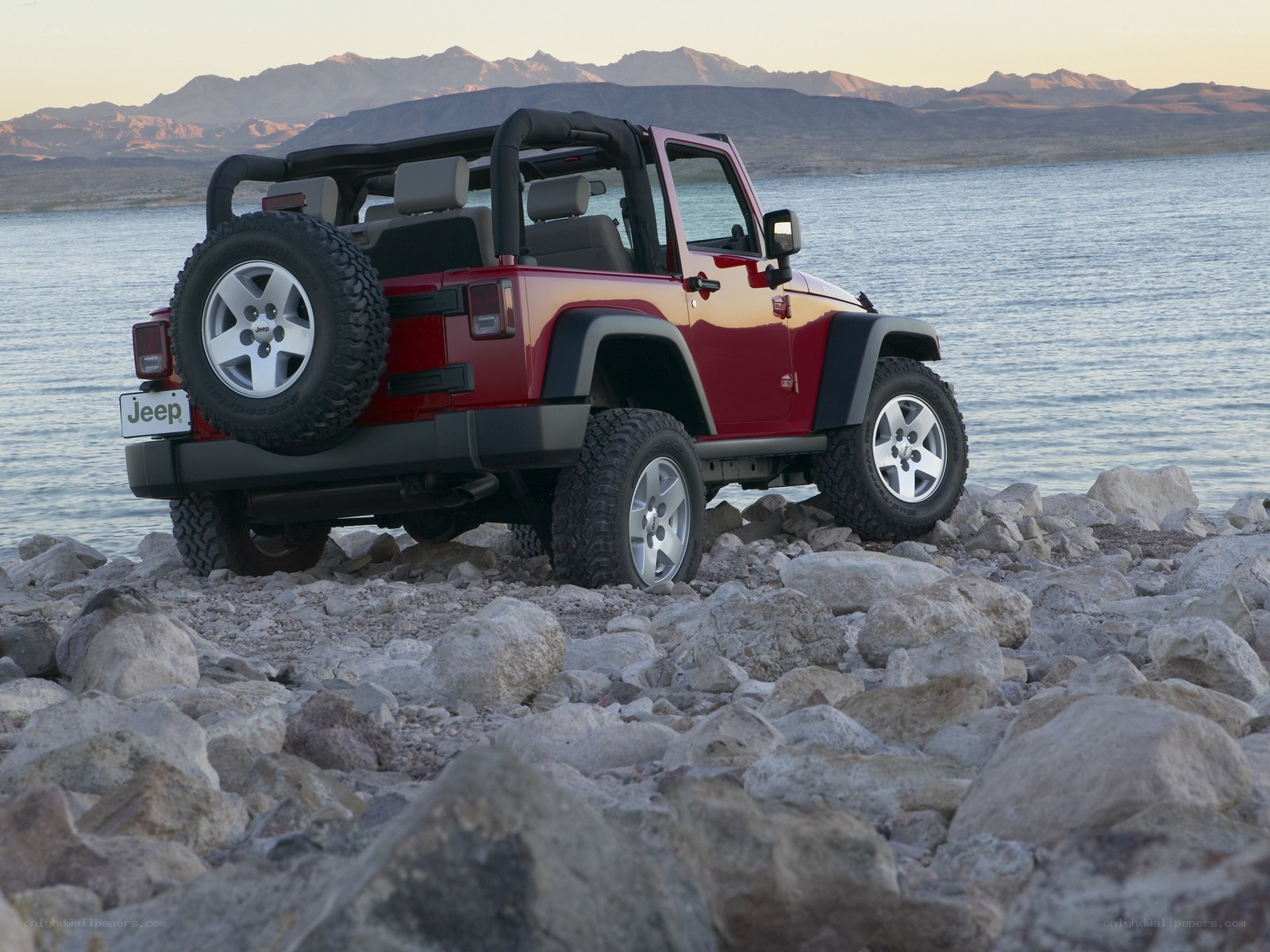 Red Jeep on rocky shore