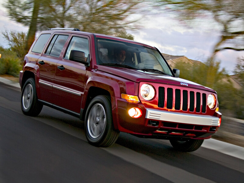 Red Jeep Patriot driving on road