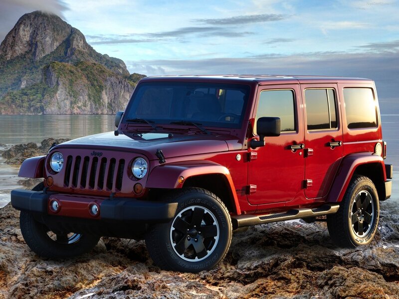 Red Jeep Wrangler on rocky shore