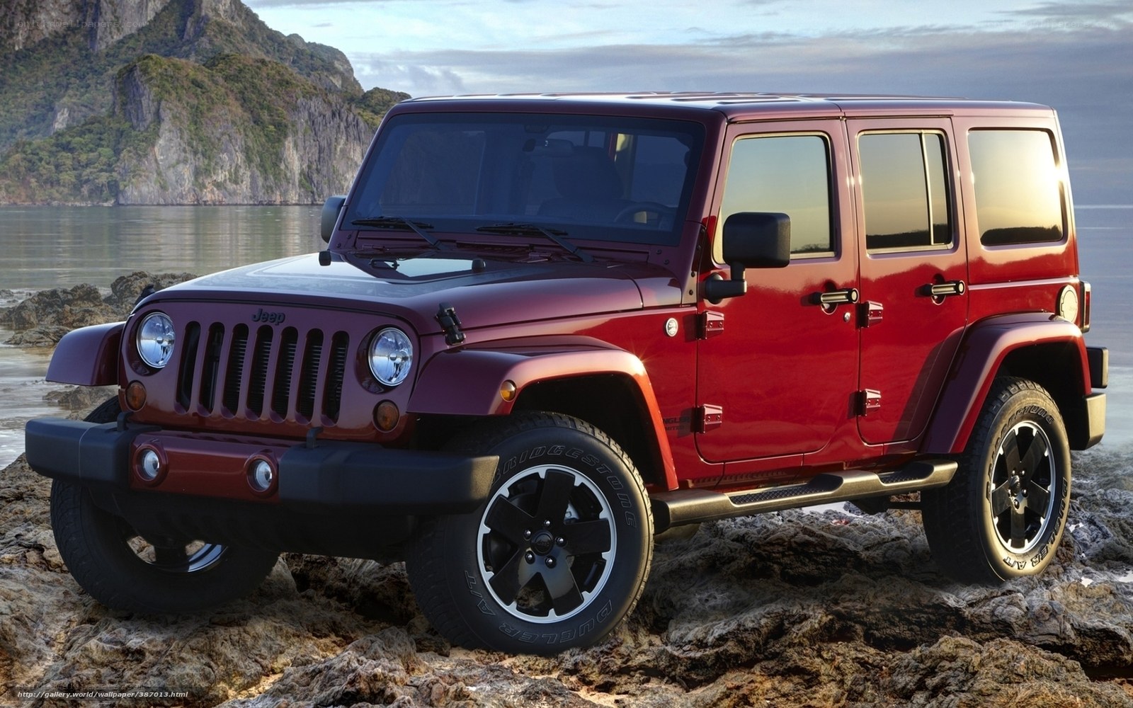 Red Jeep Wrangler on rocky shore